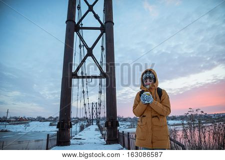 whoman trying to worm up with coffie on sunrise in cold day