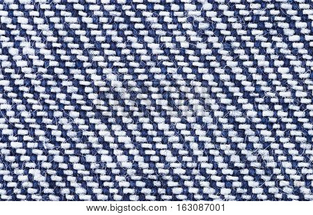 Denim textile macro photo. Surface of sturdy cotton warp-faced fabric. Twill, type of textile weave with pattern of diagonal parallel ribs. Warp thread is dyed indigo blue, weft thread is left white.