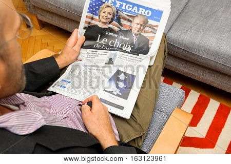 PARIS FRANCE - NOV 12 2016: Curious man reading Le Figaro French newspaper with Hillary Clinton and Donald Trump after Trump has won the elections