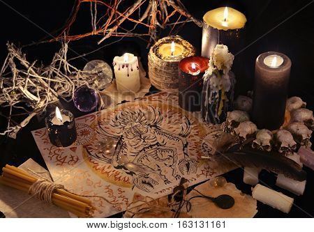 Mystic still life with demon drawing, magic objects and black candles. Halloween concept. Occult objects on table. There is no foreign text in the image, all symbols are imaginary and fantasy ones