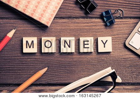 Workspace desk with keyboard office working stuff and wooden elements with the letters collected in the word money
