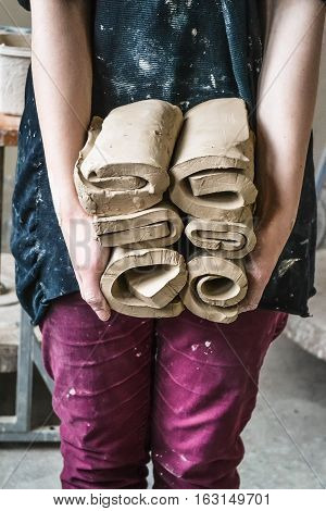 Master potter girl holding a many cut and twisted layers roll of clay pieces. Creative studio potter. Workplace wizard Crock pottery