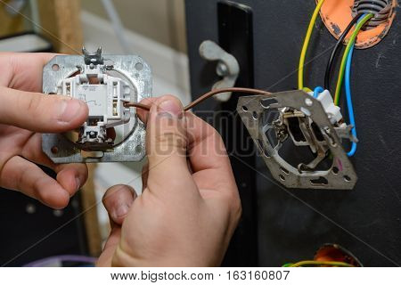 Craftsman installing and installing a switchboard - close-up installation wall