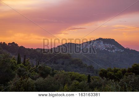 Landscape with a distant greek village on the hill at sunset. Pelekas village, Corfu, Greece