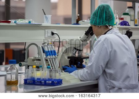 Beautiful Female Medical Or Scientific Researcher Or Woman Doctor Looking Through A Microscope In A