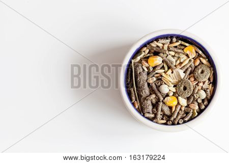 dry food for rodents in bowl on white background top view.