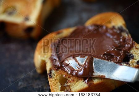 Spreading hazelnut chocolate on toasted chocolate chip brioche slices