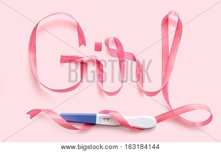 Word girl written gift ribbon pink. A positive pregnancy test. Pink background