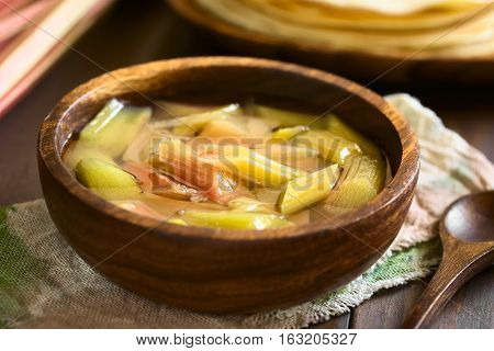 Fresh homemade rhubarb compote in wooden bowl photographed with natural light (Selective Focus Focus in the middle of the compote)