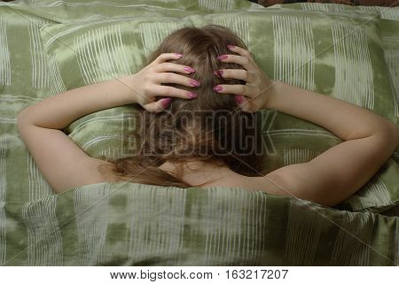 Sleeless female in bed under green blanket