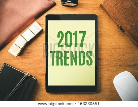 Green 2017 Trends On Tablet Screen With Clock Box,notebook,leather Bag, Pencil And Mouse On Wooden T