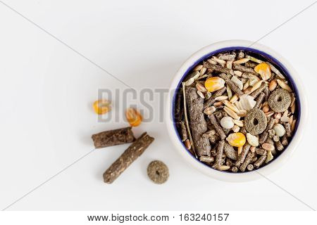 dry food for rodents in bowl on white background top view.