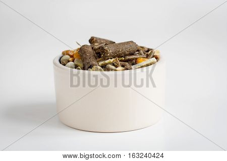dry food for rodents in bowl on white background close up