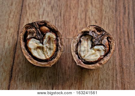 Closeup of two walnut halves with heart shaped cores on a wooden table