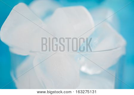 Ice cubes in a glass on blue background
