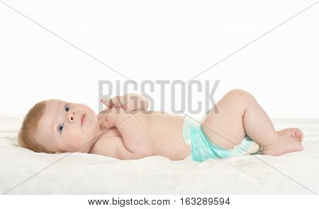 dorable baby boy in pampers on blanket on a white background