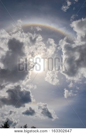 Circular rainbow with Sun and clouds sky