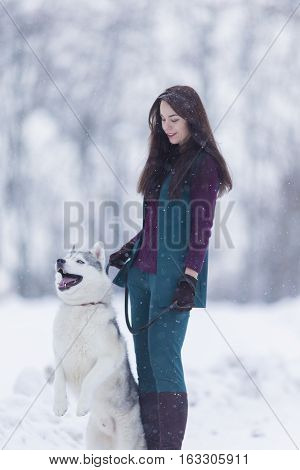 Caucasian Brunette Woman Keeping Her Husky Dog on a Short Leash During a Stroll in Winter Time Outside.Vertical Image