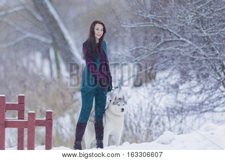 Pretty Tranquil Caucasian Brunette With Her Husky Dog during a Stroll in Winter.Horizontal Image