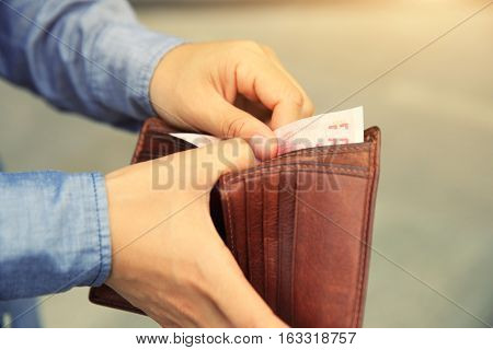 Hands taking out money from wallet on street