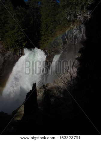 Sahalie Falls on the McKenzie River in Western Oregon full of spring run off with a small rainbow.