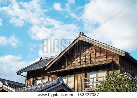 Asia culture concept - japanese traditional historical wooden old house under golden sun and morning blue cloudy sky in Japan