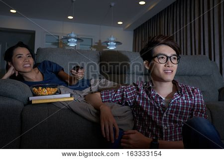 Young couple sittting at home and enjoying tv program