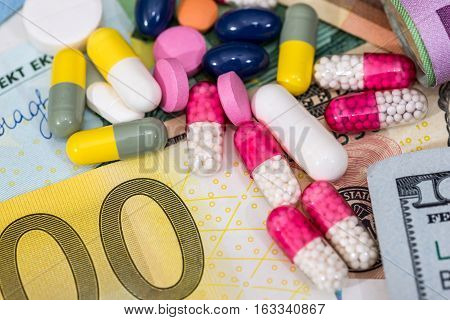 macro pills and tablets on euro and dollar banknotes for background.
