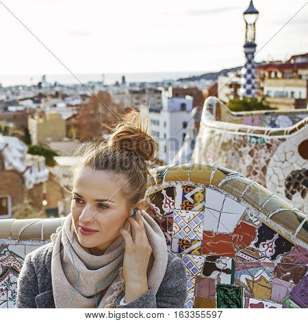 Woman In Barcelona Listening Audioguide While Sitting On Bench