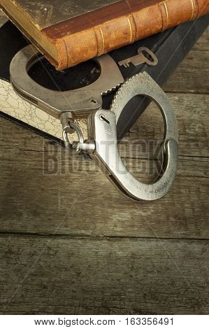 Book and handcuffs on a wooden table. The concept of punishment and justice. Punishment for a crime. Corruption and punishment. Arrest criminals.
