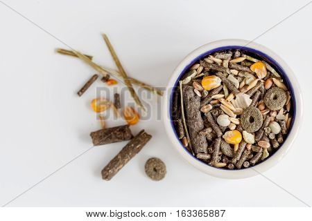 dry food for rodents in bowl on white background top view.