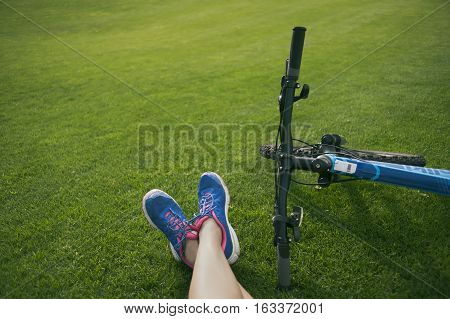 female feet on the grass in the Park near the bike