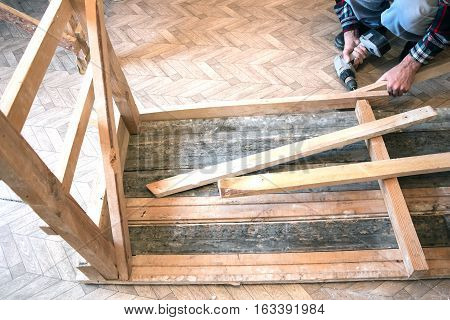 Man Screwing a screw into the wood element by means of the electrical screwdriver 2