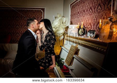 Young couple posing near piano in the dark