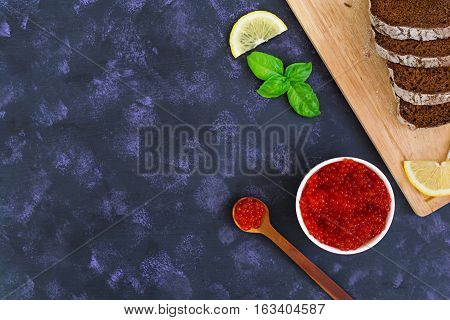Red caviar on dark background. Top view.