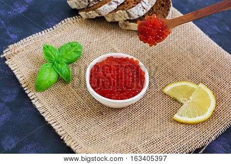 Red caviar with bread on dark background.