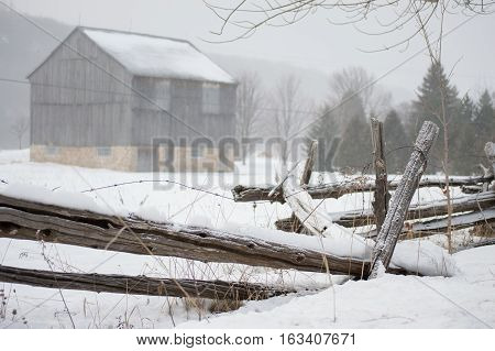 An ontario bank barn with split cedar rail fence in the snow in winter