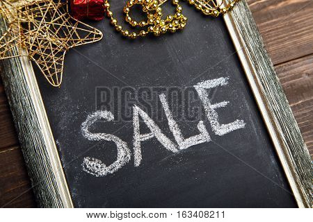 Chalkboard with Sale caption and Christmas decorations on the brown wooden table