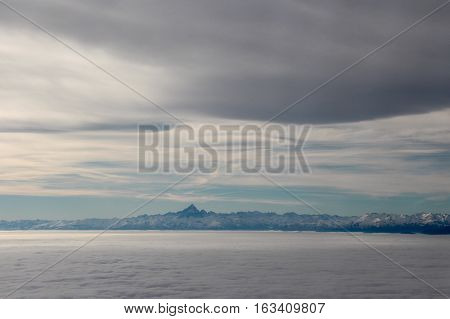 Airview of the sky with clouds and Mont Blanc at horizon.
