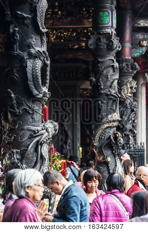Taipei, Taiwan - Dec. 3 : Asia culture concept - people pray for god in famous heritage landmark the traditional old oriental Chinese temple lungshan with with beautiful dragon pillar decoration at Dec. 3 2016