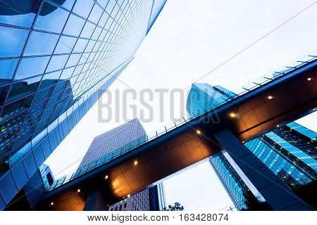 Business concept for real estate and corporate construction - looking up view in financial district the silhouettes of skyscrapers city reflect dramatic blue sky sun lights in Tokyo Japan