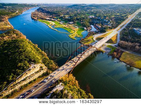 amazing austin view at Pennybacker Bridge aerial view straight down above modern architecture spanning colorado river 360 bridge with boat going by Texas Hill country with traffic and cars driving transportation