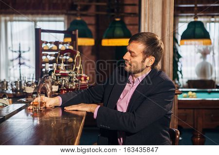 Smiling attractive young barman wiping glasses and talking to young man in bar, the man came to relax in a bar and drink
