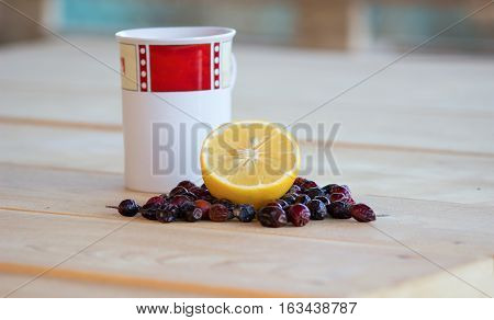 lemon and dried rosehips red and white mug dried rosehips whole and crushed and everything resting on a wooden table