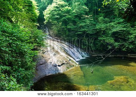 Japan travel concept - beautiful yoro keikoku valley waterfall under dramatic sun glow and morning blue sky in Chiba Prefecture Japan