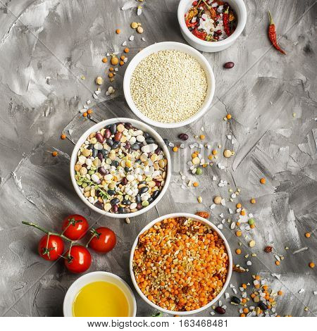 Lentils, bulgur, wheat cereal, dried tomatoes and onion with olive oil on a marble background. Ingredients for dinner. Top view. Ready-mix for soup