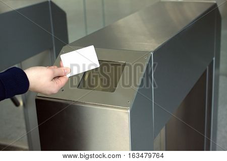 Woman's hand puts white plastic card indoor to electronic reader security access control system. Closeup view