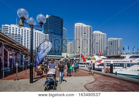 SIDNEY - AUSTRALIA NOVEMBER 2, 2016: Visitors walk along the promenade at Darling Harbour, past the Sea Life Aquarium. The waterfront is one of the city's largest dining, shopping and entertainment districts and a popular destination for visitors.