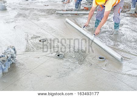 Mason is using a trowel to finish top of the concrete foundation.