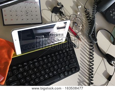 Modern workspace with tablet on mobile wireless keyboard on shared office space environment for freelance or contract work with multiple screens reflections background image